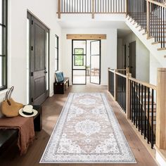 a large rug is on the floor in front of an entryway with stairs and windows