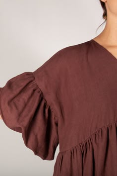 a woman wearing a brown top with ruffled sleeves