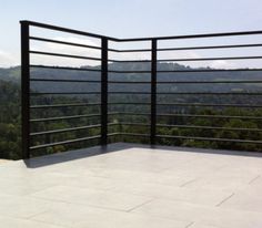 a balcony with black railings and trees in the background