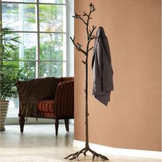 a coat rack with an umbrella on it next to a chair and potted plant