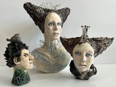 three clay sculptures of women with hats on their heads and hair in the shape of people's heads