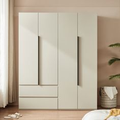 a bedroom with a bed and white cupboards next to a potted palm tree