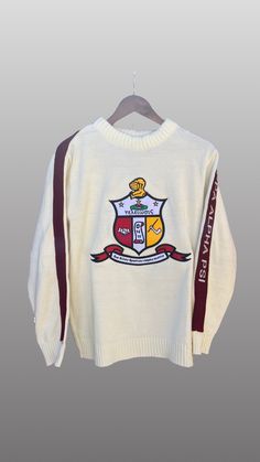 Exclusive Kappa Alpha Psi Chenille Appliqué Embroidery Crimson Sweater. This is the perfect long-sleeved Sweater to wear while showing off your Kappa Alpha Psi fraternity . A comfortable 100% Acrylic with a Chenille K diamond and Kappa Alpha Psi embroidery across the chest give you the perfect fit. This sweater is also a perfect gift for your favorite Kappa Man. Fast Shipping & Processing: 1-2 days to process US Domestic Shipping: 3-5 business days International Shipping: 7-14 business White Long Sleeve College Sweater, White Long Sleeve Sweater For College, White Embroidered Logo Sweater For Fall, White Outerwear With Embroidered Graphics, White Long Sleeve Outerwear With Embroidered Graphics, Embroidered Long Sleeve Tops For College, Embroidered Long Sleeve College Sweater, Long Sleeve Sweater With Embroidered Logo For Winter, White Long Sleeve Sweater With Embroidered Logo