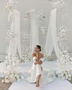 a woman sitting on top of a white rug covered in flowers and branches next to an archway