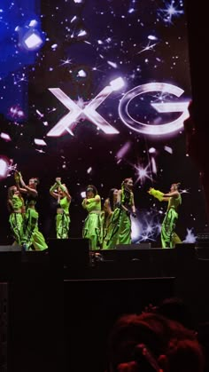 a group of people standing on top of a stage in front of a large screen