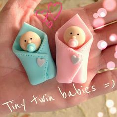 two tiny baby dolls are in the palm of someone's hand with pink and blue decorations