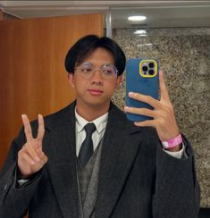 a man in a suit and tie holding up his phone