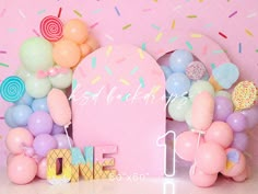 a pink backdrop with balloons and confetti