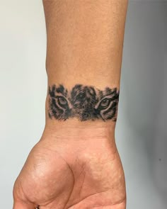 a person's hand with a tattoo on the wrist that has two tigers on it