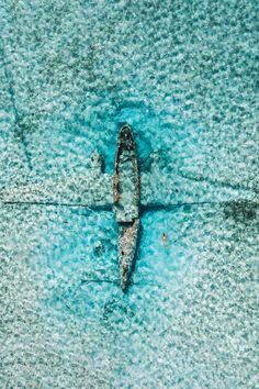 an aerial view of a small boat in the middle of blue water with two people on it