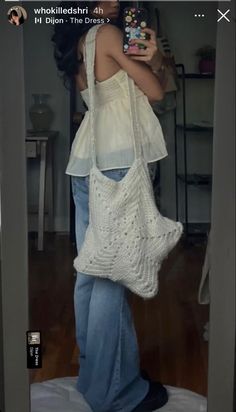 a woman is taking a selfie with her cell phone while wearing a white crochet bag