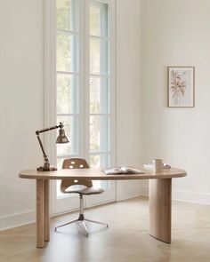 an office desk with a lamp on it in front of two windows and a chair