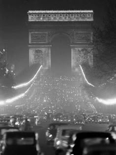 cars are driving down the street in front of the arc de trioe triumph at night