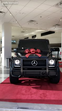 a mercedes g - class with a bow on the hood is parked in a showroom