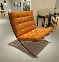 a brown leather chair sitting on top of a metal frame in a room with tables and stools