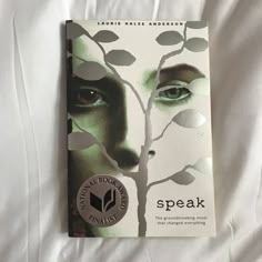 the book speak is laying on top of a white bed sheet with an image of a woman's face