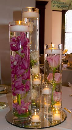 flowers and candles are arranged in glass vases