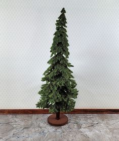 a small christmas tree on a stand in front of a wall with a white background