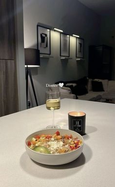 a bowl of food and a glass of wine on a table