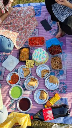 people sitting on a blanket eating food