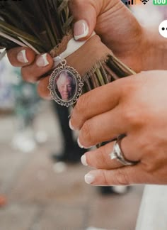 a woman holding flowers and a ring with a picture on it's middle finger