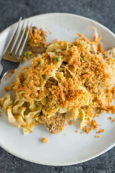 a white plate topped with macaroni and cheese covered in sauce next to a fork