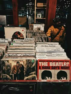 the beatles record collection is on display in front of a man sitting next to it