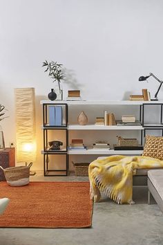 a living room filled with lots of furniture next to a wall mounted book shelf and lamp