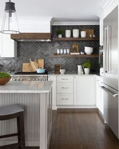 a kitchen with white cabinets and wooden shelves on the wall, along with a marble counter top