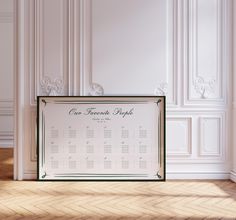 a white and green wedding seating chart on a wooden floor in front of a wall