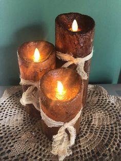 three lit candles sitting on top of a doily