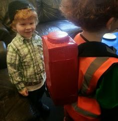 two young boys standing next to each other in front of a fire extinguisher