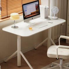 a white desk with a computer on it and a glass of orange juice in the foreground