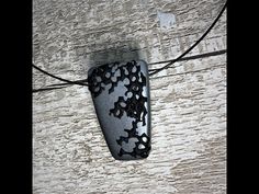 a black and white pendant hanging from a string on a wooden wall with an electrical cord