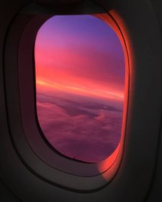 an airplane window with the view of clouds and sunset in the sky as seen from inside