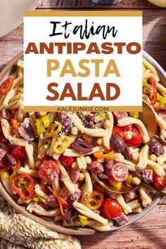 pasta salad with tomatoes, olives and peppers in a bowl on a wooden table