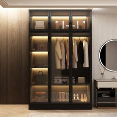 a walk in closet with clothes and shoes on the shelves next to a mirror that is lit up