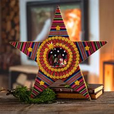 a colorful christmas star clock sitting on top of a wooden table next to a book