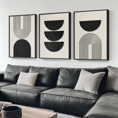 three black and white paintings hang on the wall above a leather couch in a modern living room