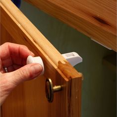 a person opening a wooden door with a white handle