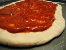 a pizza dough with sauce on it in a pan