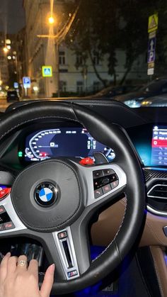 a person driving a car at night on the street with their hand on the steering wheel