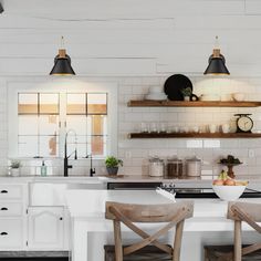 two wooden chairs sitting in front of a white kitchen counter with open shelving above it