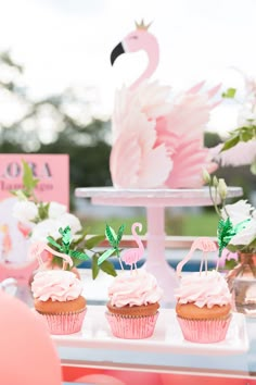 cupcakes with pink frosting and flamingos on top are sitting on a table