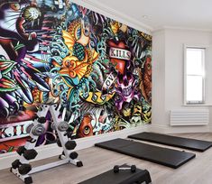 there is a mural on the wall behind exercise equipment in this home gym area with treadmills and yoga mats