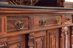 an old wooden dresser with brass handles and knobs on the doors, in a room