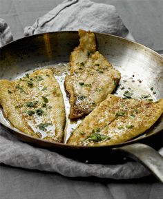 four pieces of fried food in a pan with a cloth on the table next to it