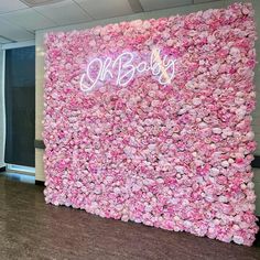 a pink flower wall with the word baby written on it in white letters and neon lights