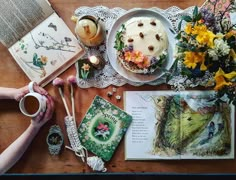 a table topped with books and flowers next to a cake on top of a wooden table