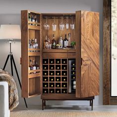 a wooden cabinet with wine glasses and bottles in it next to a white couch on the floor